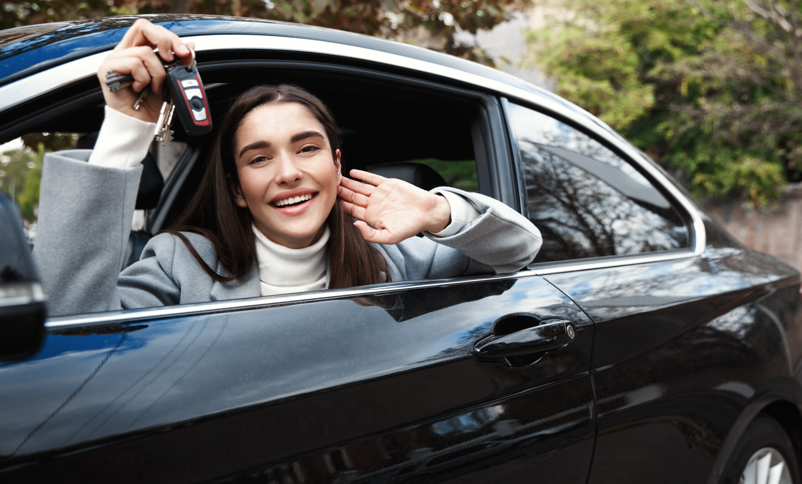 Happy woman looking out window, holding car keys.